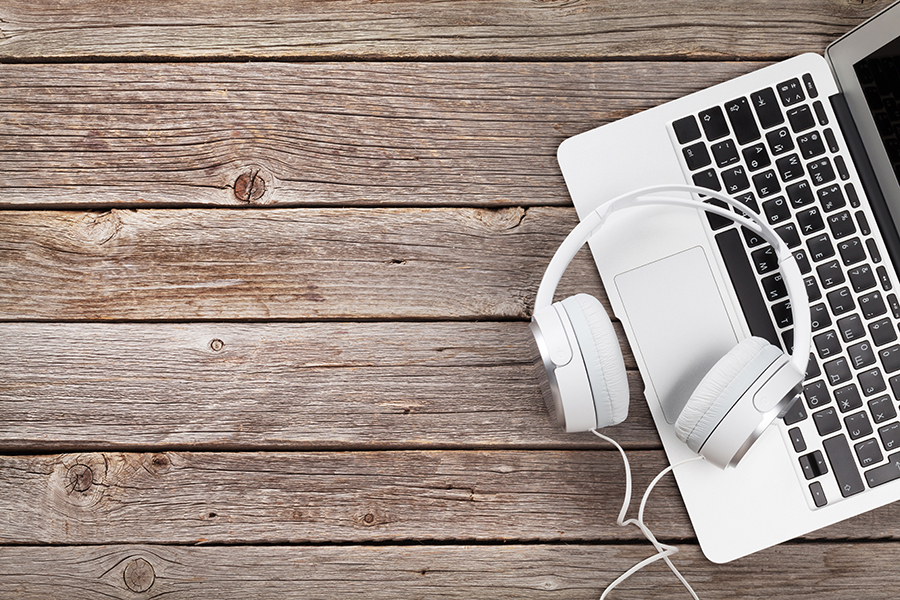 Headphones over laptop on wooden desk table. Music concept. Top view with copy space